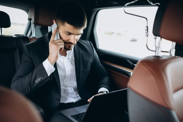 Corporate client relaxing inside a luxury black limousine with leather seats.
