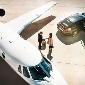 Private jet arrival with a luxury chauffeur greeting a passenger on the tarmac.