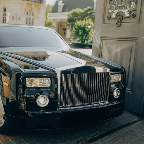 Black Rolls-Royce luxury car parked at an exclusive venue.