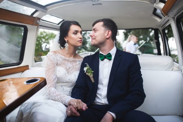 A married couple sitting in a luxurious limousine, gazing lovingly into each other's eyes.