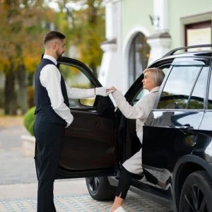 A professionally dressed man and woman stepping out of a luxury black limousine in an urban setting.